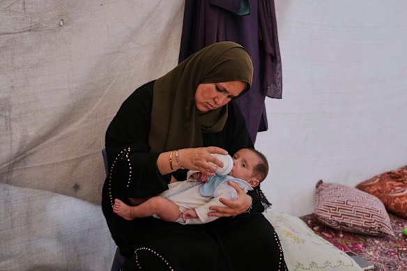 A mother feeds her daughter at a refugee camp in Khan Younis.