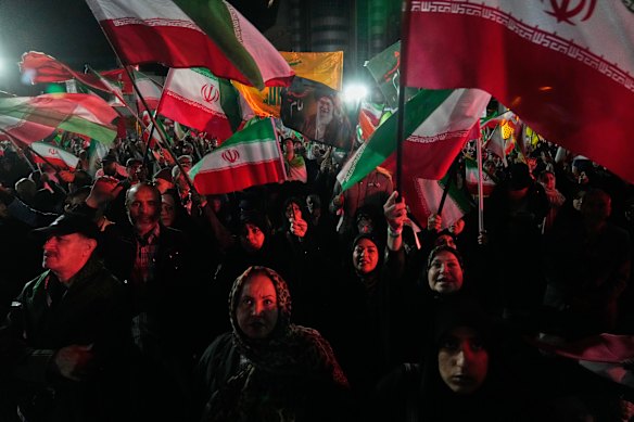 Lunedì i manifestanti filogovernativi sventolano bandiere iraniane a Teheran.