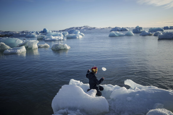 A boy throws ice into the sea in Nuuk, Greenland, on Tuesday.