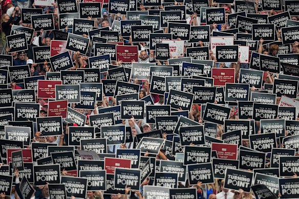 People hold up signs during a memorial for conservative activist Charlie Kirk.