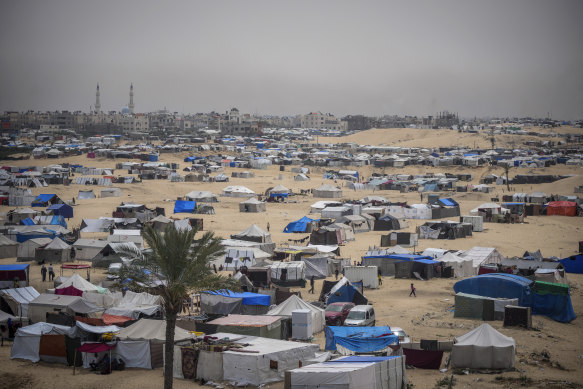 Palestinians displaced by the Israeli air and ground offensive on the Gaza Strip walk through a makeshift tent camp in Rafah.