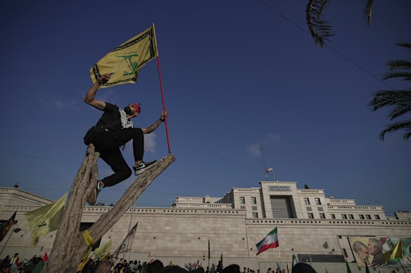 A Hezbollah supporter takes a selfie while waving a Hezbollah flag as he stands on a tree outside the Iranian Embassy in Beirut.