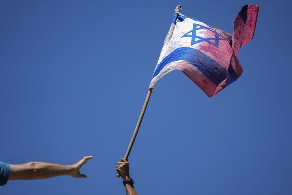 A demonstrator waves a coloured Israeli flag during a protest.