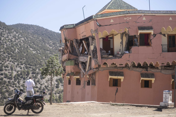 A man stands next to a damaged hotel after the earthquake.