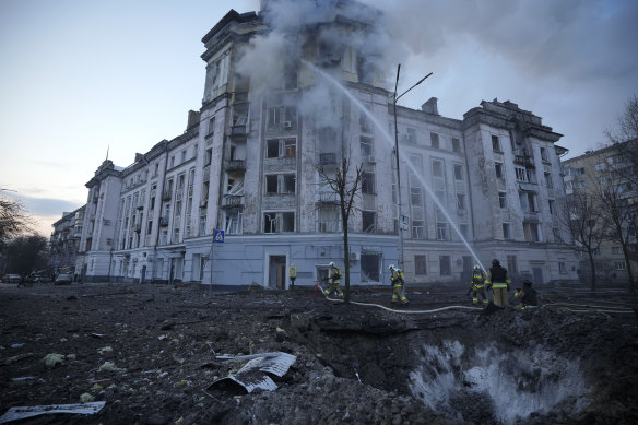 Firefighters work near the crater at the site after Russian attacks in Kyiv, Ukraine, on Thursday.