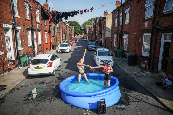 Residents take a dip in a paddling pool to cool off outside their home in Leeds, England in July 2022. 