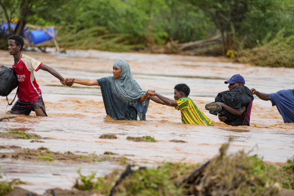 Residents cross a road damaged by El Niño rains in Tula, Tana River county in Kenya.