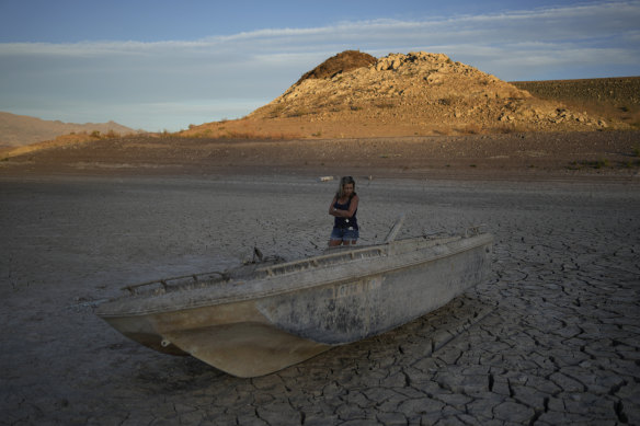 Misha McBride looks at a formerly sunken boat now on cracked earth more than 100 metres from what is now the shoreline on Lake Mead, Nevada.