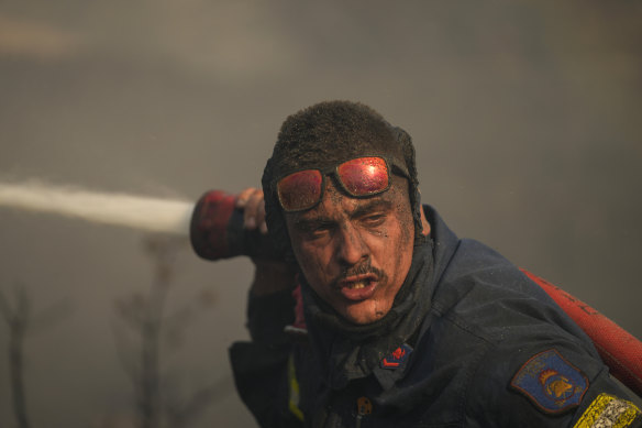 A firefighter sprays water at a fire on the mount of Penteli in Greece in July.