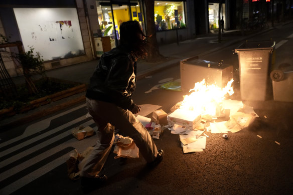 A protester walks past burning garbages during a protest in Paris on Saturday.