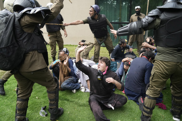 The cricketer turned politician was not home when Pakistani police stormed his residence and arrested 61 people amid tear gas and clashes.