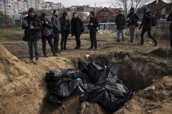 Journalists stand by a mass grave in Bucha on Monday.