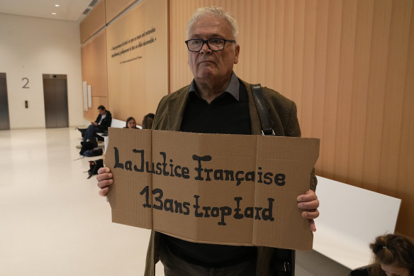 A man holds a placard reading “The French justice, 13 years too late” prior to the start of the trial of Airbus and Air France companies.