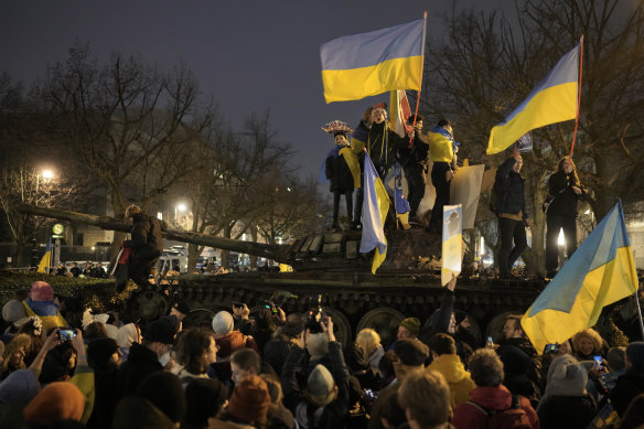 People wave Ukrainian flags as they stand on top of a wreck of a destroyed Russian tank placed in front of the Russian Embassy during a demonstration to mark the first anniversary of Russia’s full-scale invasion of Ukraine, in Berlin.