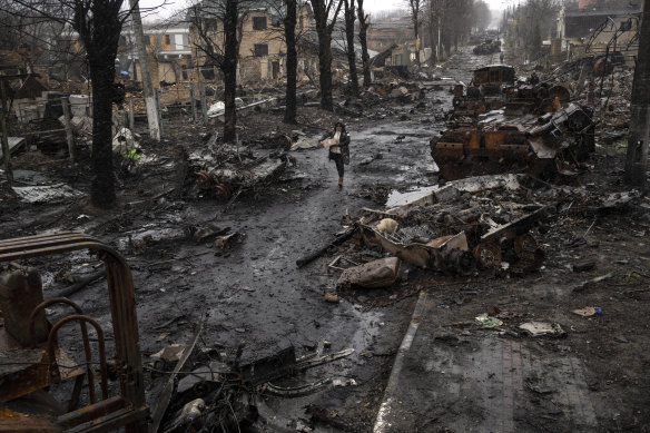 A woman walks amid destroyed Russian tanks in Bucha, in the outskirts of Kyiv.