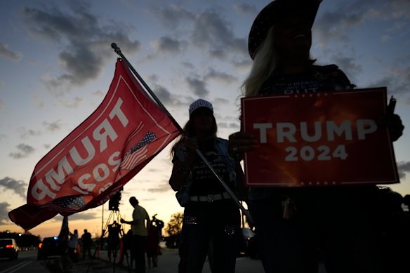 The sun sets as two women show their support for former president Donald Trump near his Mar-a-Lago estate in Palm Beach, Florida. 