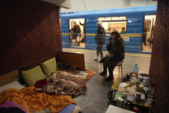 A woman sits among her belongings and food in a Kyiv train station. 