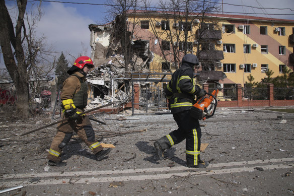 Firefighters walk past a building in Mariupol damaged by shelling on Thursday.