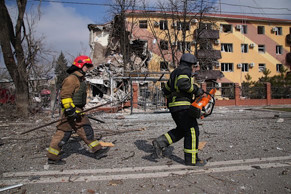 Firefighters walk past a building in Mariupol damaged by shelling on Thursday.