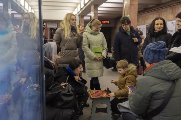A boy and a woman play chess as other people watch in a subway station being used as a bomb shelter during a Russian rocket attack in Kyiv, Ukraine.