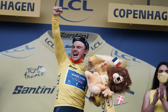 Stage winner Belgium’s Yves Lampaert, wearing the overall leader’s yellow jersey, celebrates on the podium.
