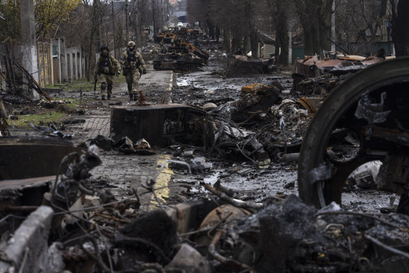 Soldiers walk amid destroyed Russian tanks in Bucha, on the outskirts of Kyiv, in April 2022.