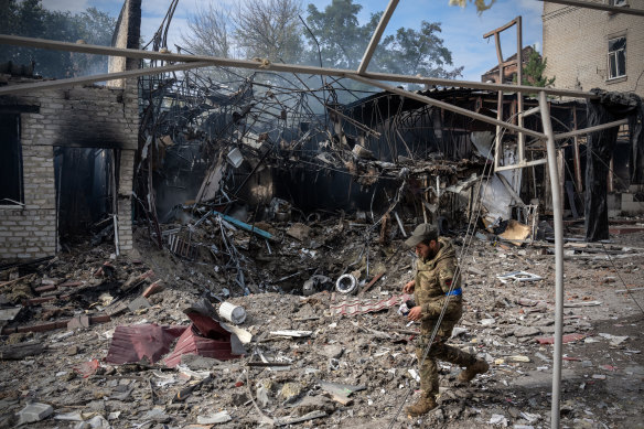 A soldier passes the crater where a Russian missile struck a shopping area earlier in the day in Kupiansk.