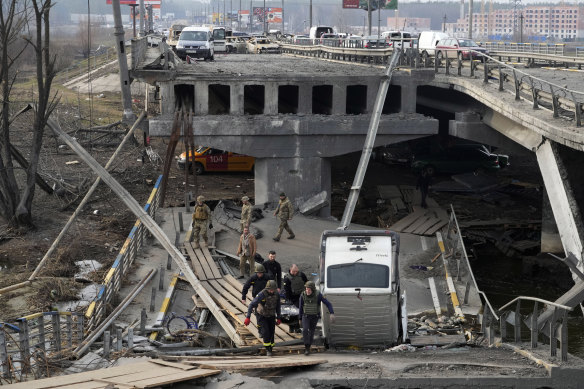 Ukrainian soldiers carry a body of a civilian killed by the Russian forces over the destroyed bridge in Irpin close to Kyiv, Ukraine, on Thursday.