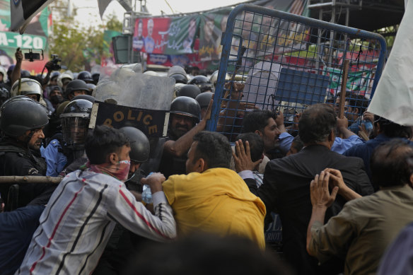 Supporters of former Prime Minister Imran Khan’s party scuffle with riot police officers outside Khan’s residence, in Lahore. An order has been issued for his arrest for failing to appear in court on corruption charges.