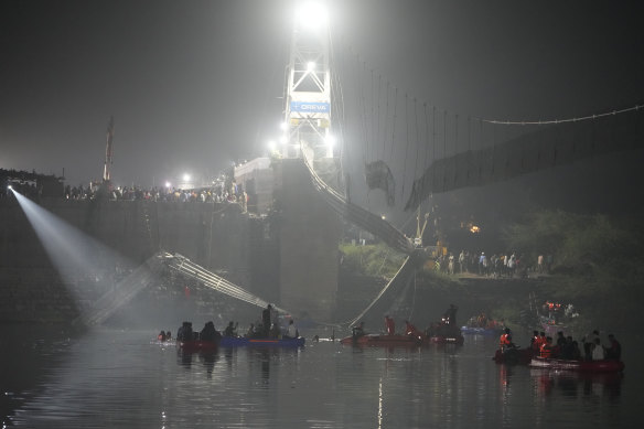 Rescuers on boats search in the Machchu river next to the collapsed cable bridge.