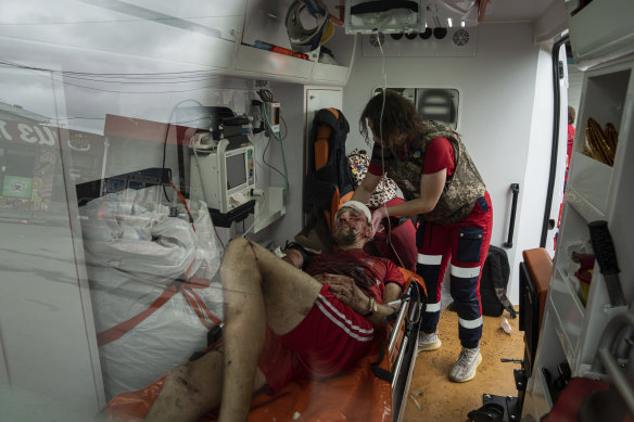 A paramedic assists an injured man in an ambulance after a Russian attack at Barabashovo market in Kharkiv, Ukraine, on Thursday.