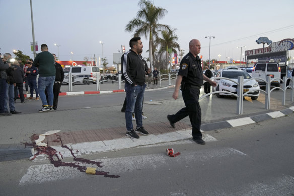 Blood stains a road after as policemen work at the scene of an attack in Beersheba, southern Israel.