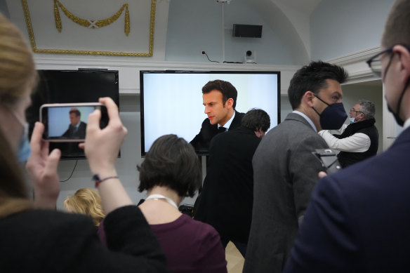 Journalists watch as French President Emmanuel Macron speaks with Russian President Vladimir Putin at the Kremlin.