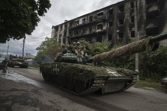 Ukrainian servicemen drive atop a tank in the recently retaken area of Izyum.