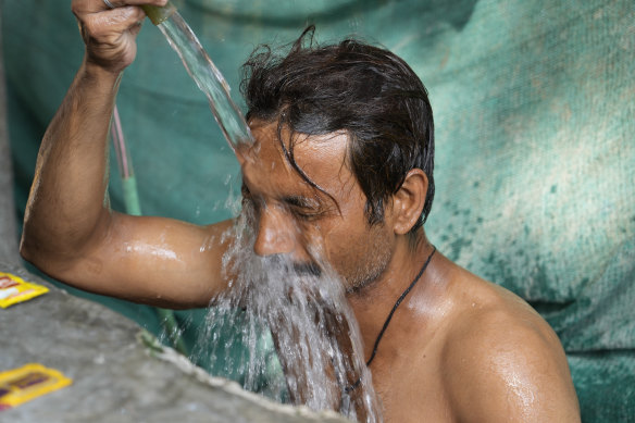A man bathes at a public water tap during a hot summer afternoon in Lucknow in the central Indian state of Uttar Pradesh, Thursday, April 28, 2022.