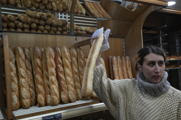 Mylene Poirier talks to a customer as she takes a baguette at a bakery in Versailles, west of Paris.