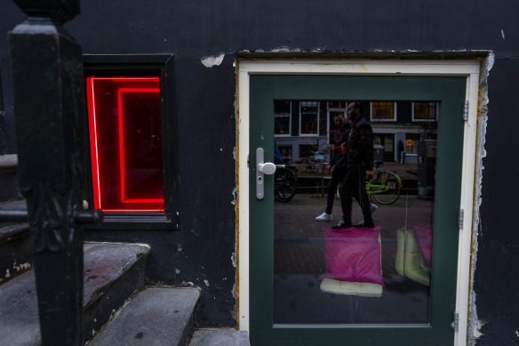 People pass the window of a sex worker with her empty seat in the Red Light District of Amsterdam during a COVID lockdown on December 30, 2021.