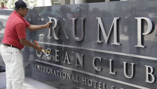 A man removes the word Trump, off a marquee outside the Trump Ocean Club International Hotel and Tower in Panama City.