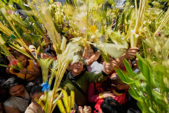 Devotees wave their palm fronds during blessing rites outside the Antipolo Cathedral in Antipolo city, Philippines as they observe Palm Sunday.