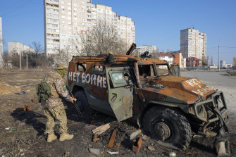 A Ukrainian soldier inspects a destroyed Russian military vehicle after a recent battle in Kharkiv.  The graffiti on the car says ‘No to war’.