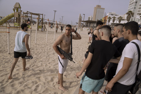 An off-duty Israeli soldier carries his rifle on the beach in Tel Aviv.