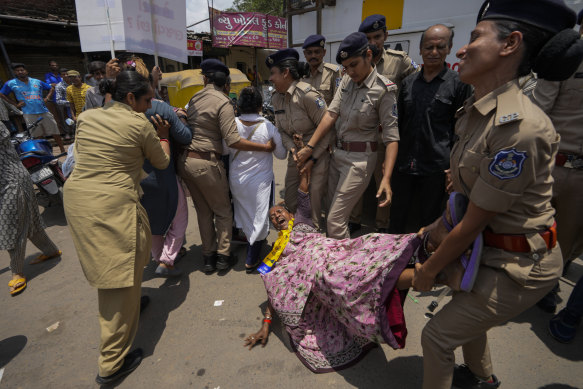 Police detains a supporter of the Aam Aadmi Party during a rally against women’s oppression in Ahmedabad.