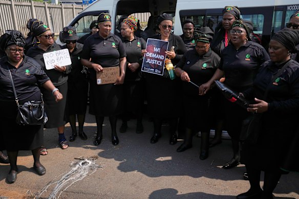Members of a women’s church group sing next to a melted candle as they pay their respects in Kempton Park.