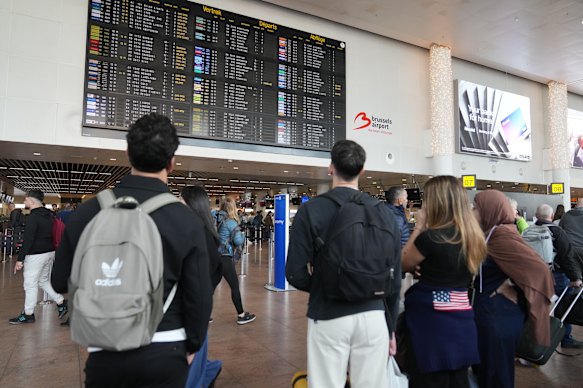 Passengers look at a departure board after cancellations and delays following the latest drone incursion, this time over Brussels Airport this week.