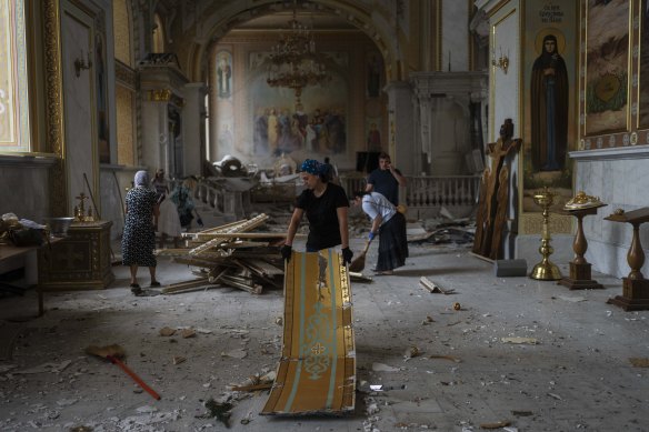 İnsanlar, Rusya tarafından bombalandıktan sonra Başkalaşım Katedrali'nin içini temizliyor.