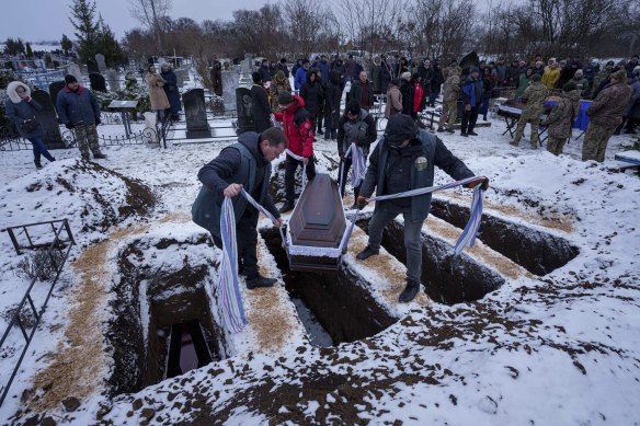 Funeral workers lower the coffins of Kateryna Zapishnya, 38, Diana Zapishnya, 12, Danyil Zapishnyi, 8, and Serhii Zapishnyi, 40, who were killed on February 1 by a Russian strike on a residential building in Poltava, Ukraine.