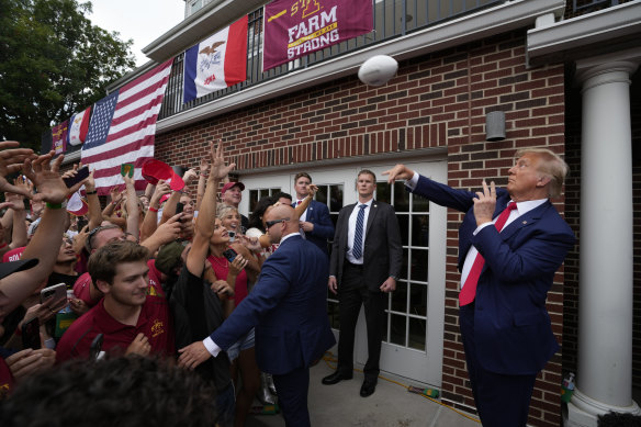 Former President Donald Trump throws a football to the crowd outside  Alpha Gamma Rho fraternity.