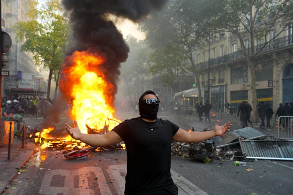 A protester gestures in front of a burning barricade during a demonstration near Place de la République.