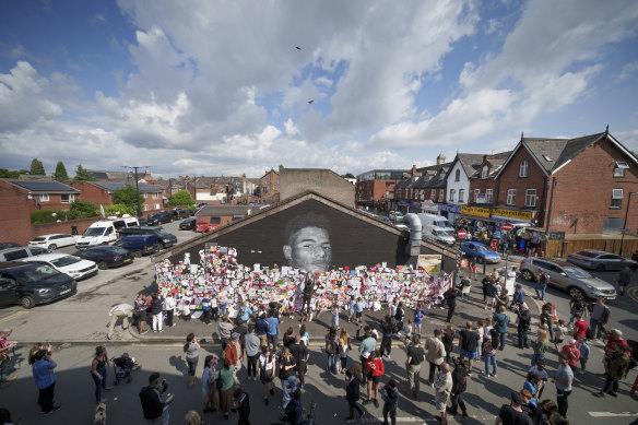 Crowds gather at the newly repaired Marcus Rashford mural in Manchester.