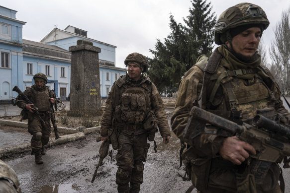 Yakın zamanda Bakhmut siperlerinden dönen Ukraynalı askerler, Ukrayna'nın Chasiv Yar kentinde bir sokakta yürüyor.